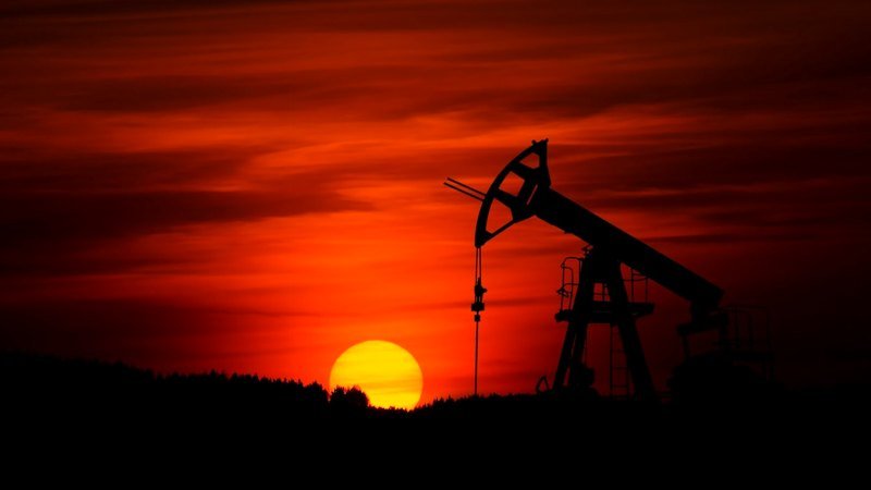 Crude oil pumpjack against a red sunset